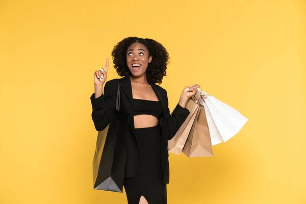 Black Woman Pointing Fingers Upward While Posing Shopping Bags Isolated — Stockfoto