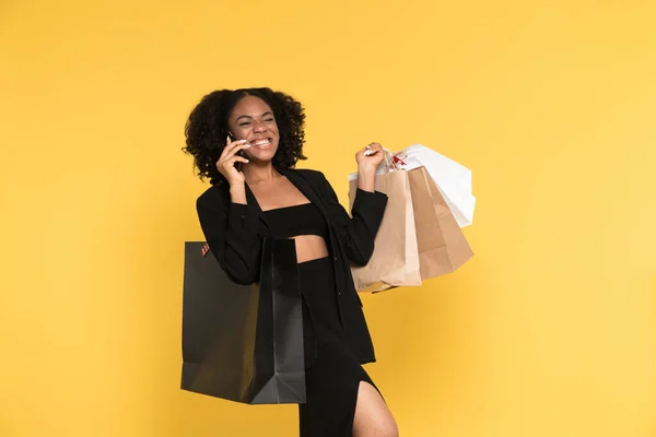 Black Woman Talking Cellphone While Posing Shopping Bags Isolated Yellow — Stock Fotó