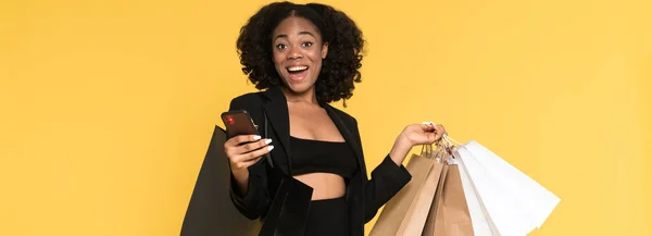 Black Woman Using Cellphone While Posing Shopping Bags Isolated Yellow — Stock Fotó