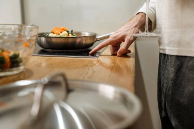 Avrupalı bir adam evde sebzelerle yemek yapıyor.