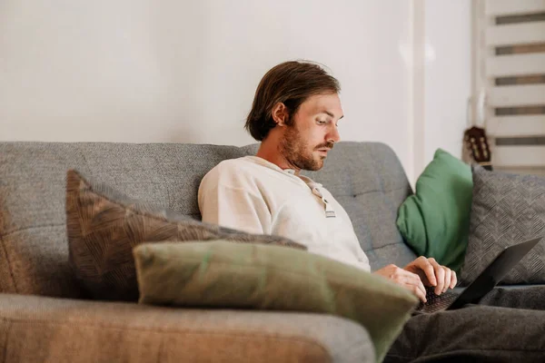 European Unshaven Man Using Laptop While Resting Sofa Home — Foto Stock