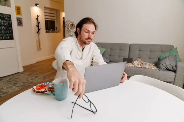 European Unshaven Man Working Laptop While Having Breakfast Home — Foto Stock