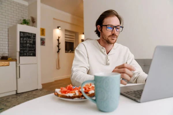 Ginger Bristle Man Eyeglasses Working Laptop While Having Dinner Home — Foto Stock