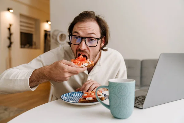 Ginger Bristle Man Eyeglasses Working Laptop While Having Dinner Home — Stockfoto