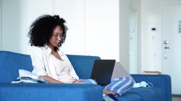 Positive Curly Haired Woman Eyeglasses Working Laptop While Sitting Sofa — Stockvideo