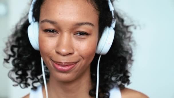 Cheerful Curly Haired Woman Listening Music Headphones Looking Camera Home — Stockvideo