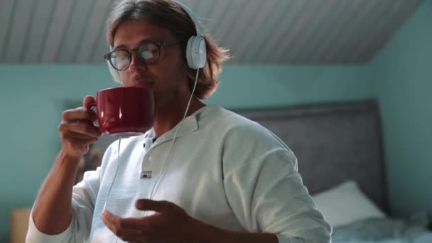 Concentrated Blond Man Wearing Eyeglasses Listening Music Headphones Drinking Coffee — Αρχείο Βίντεο