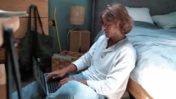 Confident Blond Man Wearing Eyeglasses Working Laptop While Sitting Floor — Vídeo de Stock