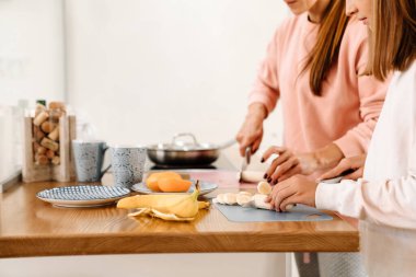 White mother and daughter cooking together in kitchen at home