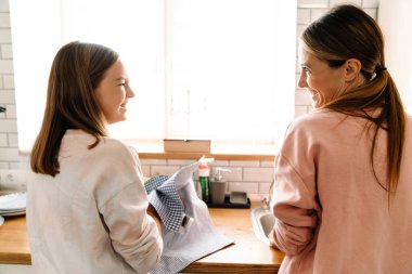 Beyaz anne ve kızı evde birlikte bulaşık yıkıyorlar.