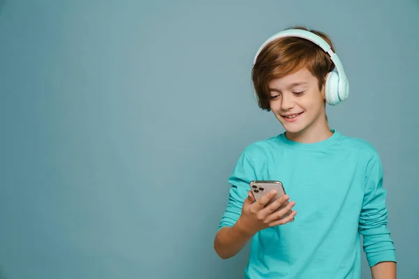 Ginger Boy Smiling While Listening Music Headphones Cellphone Isolated Blue — ストック写真