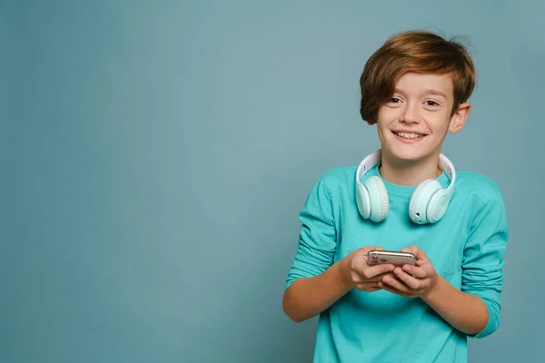 Ginger White Boy Headphones Smiling Using Cellphone Isolated Blue Wall — ストック写真