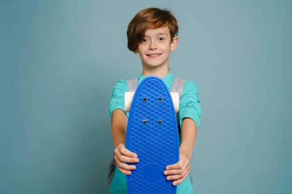 Ginger White Boy Smiling While Showing Skateboard Camera Isolated Blue — Foto de Stock