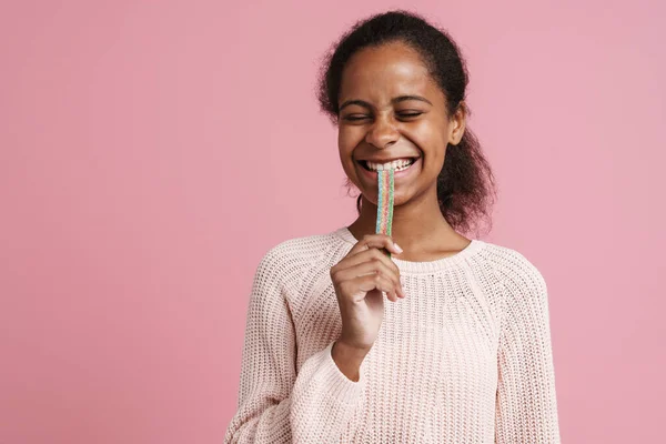 Brunette Black Girl Smiling While Eating Candy Worm Isolated Pink — стоковое фото