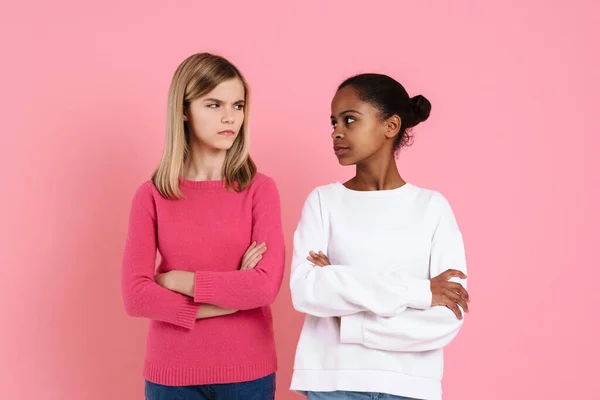 Multiracial Girls Frowning While Posing Arms Crossed Isolated Pink Wall — Stockfoto