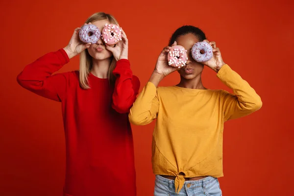 Multiracial Two Girls Grimacing While Making Fun Donuts Isolated Red — 图库照片