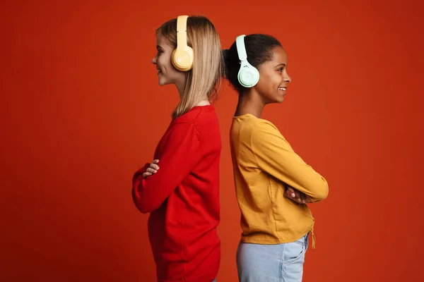 Multiracial Two Girls Smiling While Listening Music Headphones Isolated Red — Foto de Stock