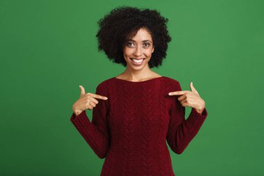 Black young woman wearing sweater pointing fingers at herself isolated over green background
