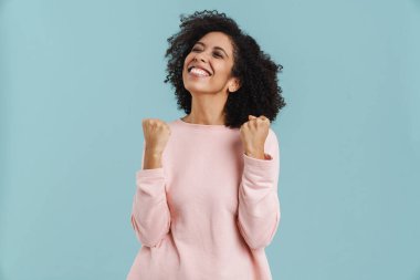 Black young woman laughing while making winner gesture isolated over blue background