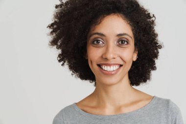 Young black woman with curly hair smiling and looking at camera isolated over white background