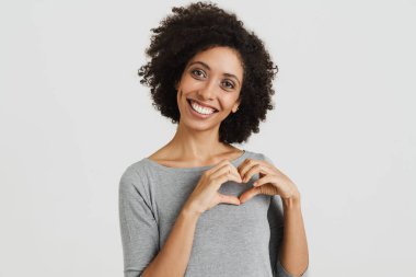 Young black woman smiling and making heart gesture isolated over white background