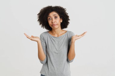 Young black woman frowning and gesturing at camera isolated over white background