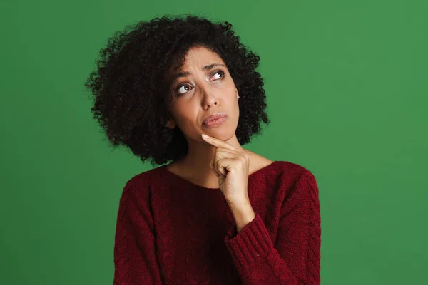 Black Puzzled Woman Wearing Sweater Looking Aside Isolated Green Background — Stockfoto