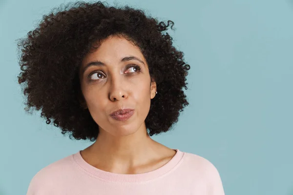 Young Black Woman Curly Hair Thinking Looking Aside Isolated Blue — Stockfoto