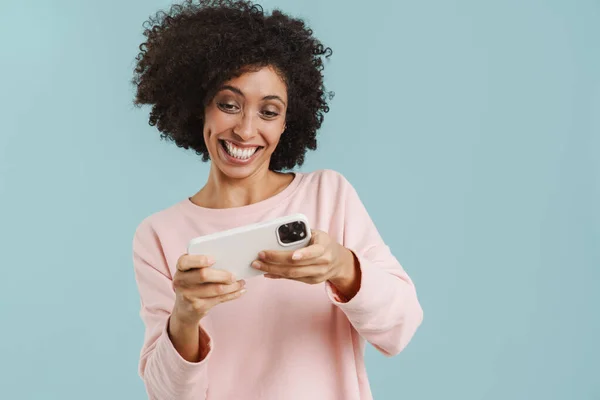 Young Black Woman Smiling Playing Online Game Cellphone Isolated Blue — Fotografia de Stock