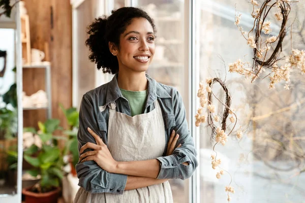 Young black ceramist woman wearing apron smiling while working in her studio