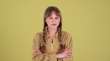 Pretty blonde woman with pigtails disagrees with something and showing stop gesture isolated over green background