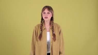 Surprised blonde woman with pigtails looking at the camera in green studio