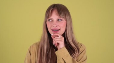 Smiling blonde woman thinking and agrees isolated over green background in studio