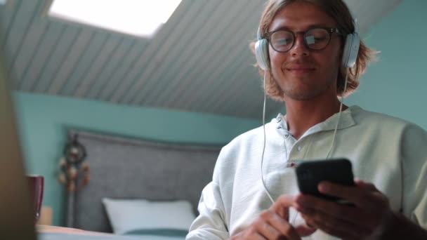 Pleased Blond Man Wearing Eyeglasses Listening Music Headphones Typing Phone — Stock videók