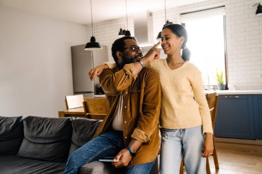 Black girl and her father laughing and using cellphone at home
