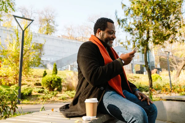 Black Man Using Cellphone Drinking Coffee While Sitting Bench Park — Stock fotografie