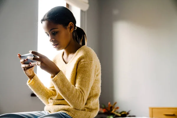 Black Brunette Girl Using Mobile Phone While Sitting Bed Home — Stockfoto