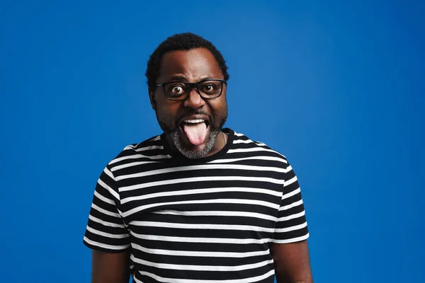 Black Excited Man Eyeglasses Showing His Tongue Camera Isolated Blue — Stockfoto