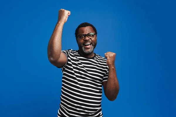 Black Man Eyeglasses Screaming While Making Winner Gesture Isolated Blue — Stockfoto