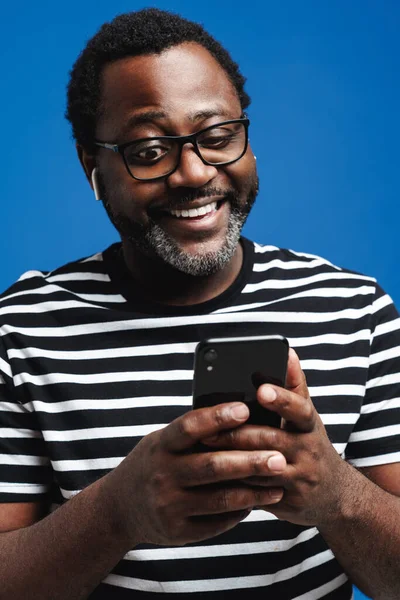Чернокожий Мужчина Наушниках Слушает Музыку Помощи Мобильного Телефона Изолированного Синем — стоковое фото