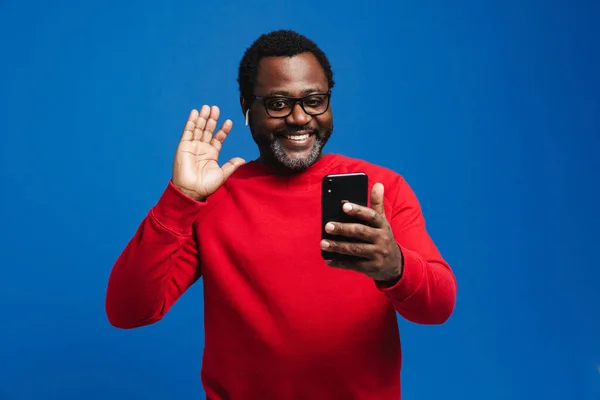 Black Man Earphones Waving Hand While Using Mobile Phone Isolated — Stock fotografie