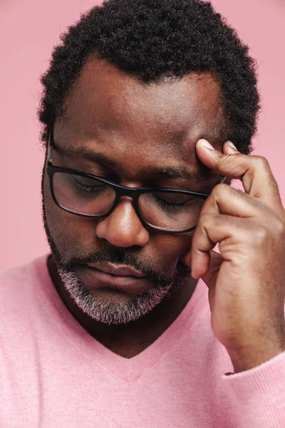 Black puzzled man in eyeglasses thinking with eyes closed isolated over pink background