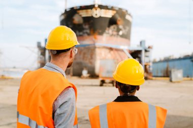 Multiracial man and woman in protective clothing talking while working at port