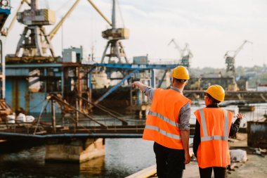 Multiracial man and woman in protective clothing working together at port