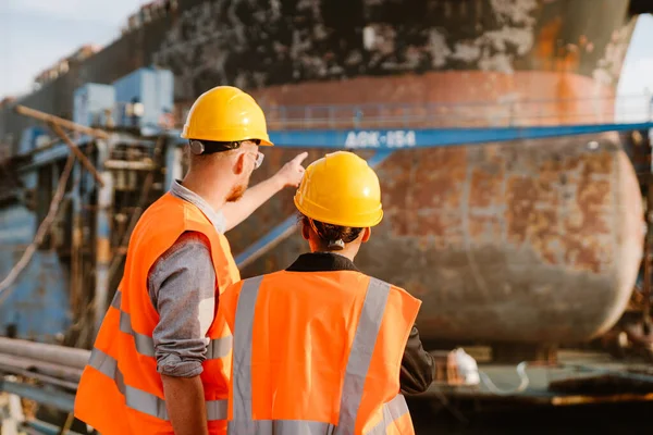 Multiracial man and woman in protective clothing working together at port