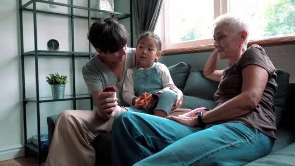Handsome mature lesbian couple talking and playing with adopted Asian daughter indoors at home