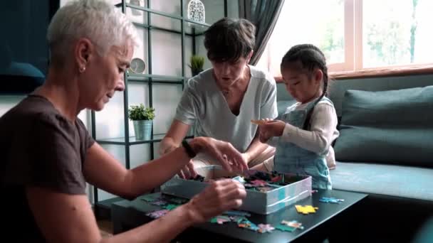 Positive Mature Lesbian Couple Talking Putting Puzzles Together Adopted Asian — Vídeo de stock