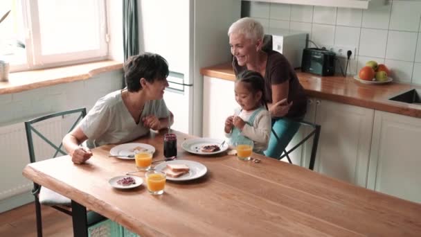 Happy Mature Lesbian Couple Talking Eating Breakfast Adopted Asian Daughter — Vídeo de stock