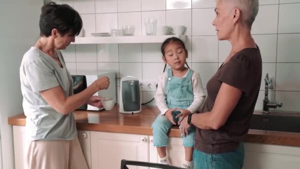 Pensive Mature Lesbian Couple Talking Adopted Asian Daughter Kitchen Home — Video