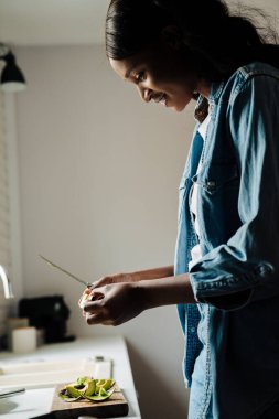 Black young woman smiling while cooking in kitchen at home